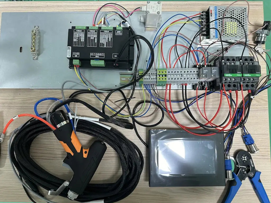 Components and wiring setup for DIY fiber laser welder on a wooden workbench