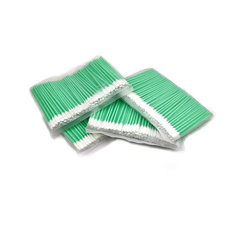 Bags of green and white cotton swabs neatly stacked on a white background